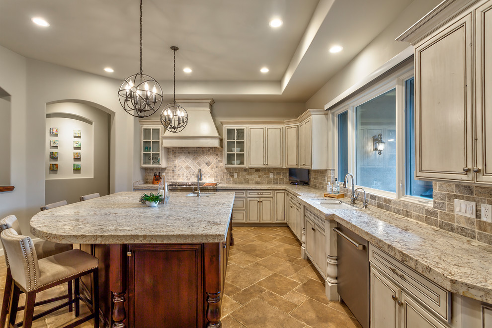 Eat-in kitchen - mid-sized l-shaped travertine floor and multicolored floor eat-in kitchen idea in Phoenix with a drop-in sink, recessed-panel cabinets, distressed cabinets, granite countertops, multicolored backsplash, travertine backsplash, stainless steel appliances, an island and multicolored countertops