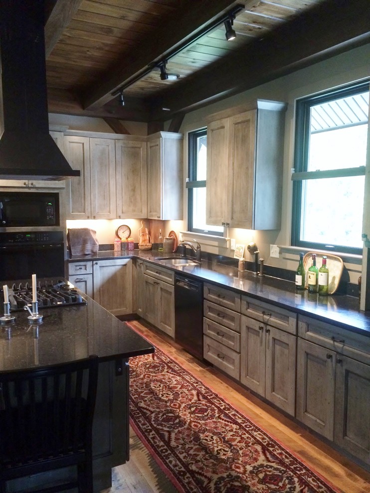Photo of a mid-sized industrial l-shaped open plan kitchen in Baltimore with an undermount sink, flat-panel cabinets, distressed cabinets, quartz benchtops, beige splashback, black appliances, light hardwood floors and with island.