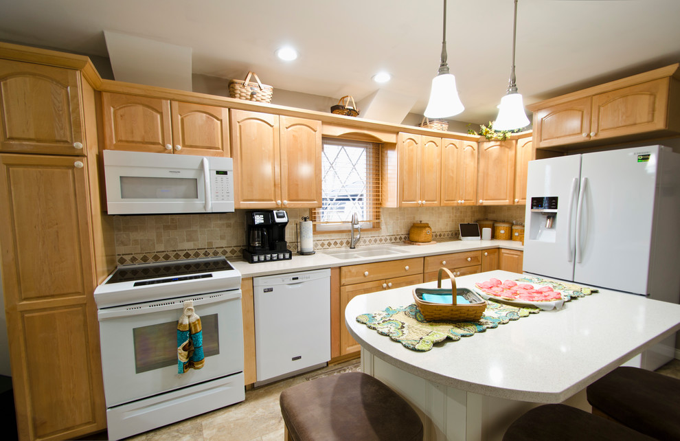 This is an example of a mid-sized traditional l-shaped kitchen pantry in Chicago with an undermount sink, raised-panel cabinets, light wood cabinets, quartz benchtops, multi-coloured splashback, travertine splashback, white appliances, vinyl floors, with island, beige floor and beige benchtop.
