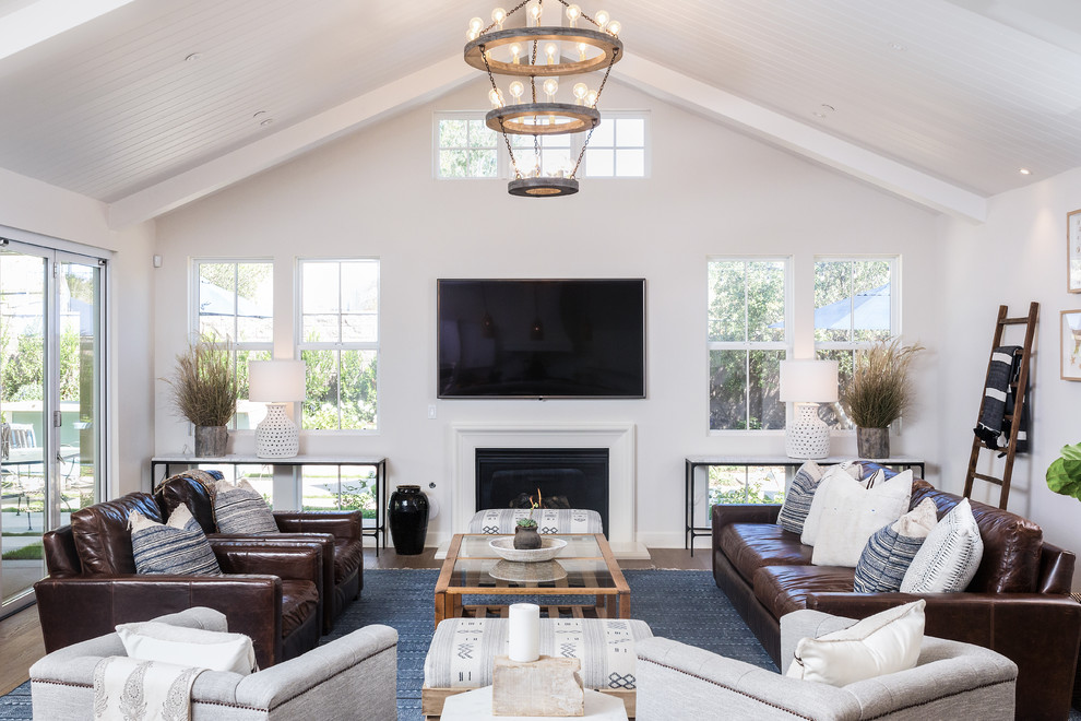 This is an example of a country family room in San Diego with white walls, dark hardwood floors, a standard fireplace and a wall-mounted tv.