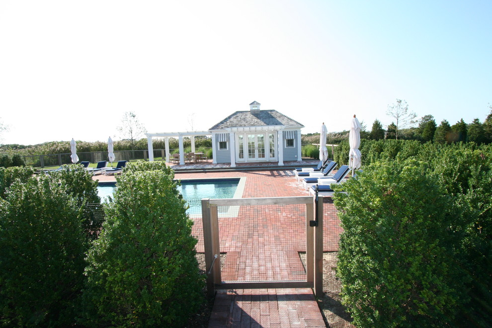 Inspiration for a mid-sized traditional backyard rectangular pool in New York with a pool house and brick pavers.