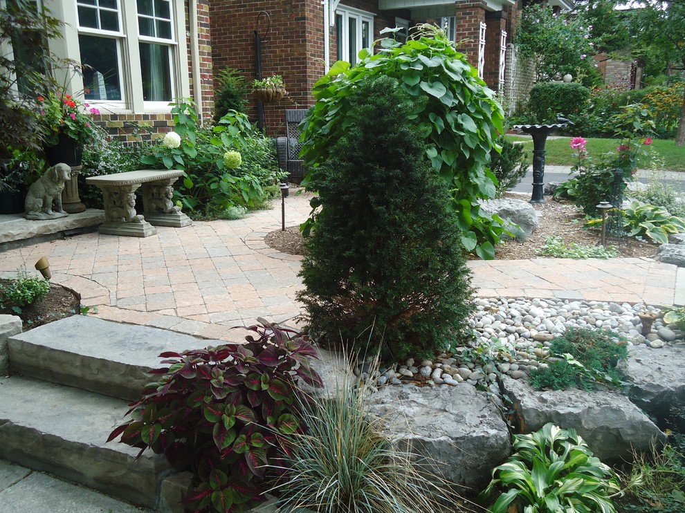 Mid-sized contemporary front yard verandah in Toronto with brick pavers.