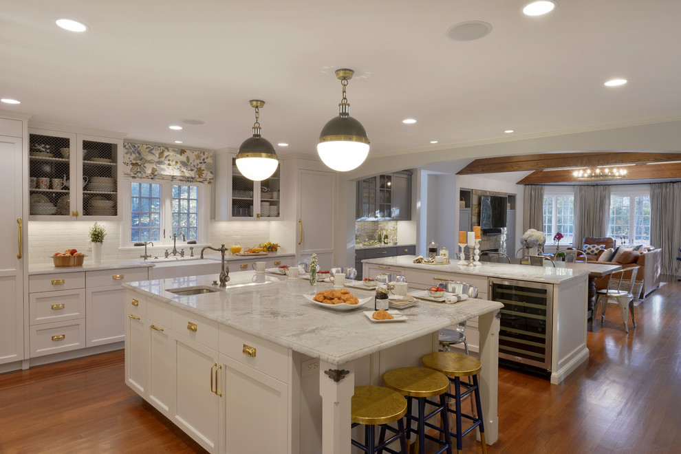 Photo of an expansive transitional l-shaped eat-in kitchen in New York with a farmhouse sink, recessed-panel cabinets, white cabinets, quartzite benchtops, white splashback, ceramic splashback, coloured appliances, dark hardwood floors and multiple islands.