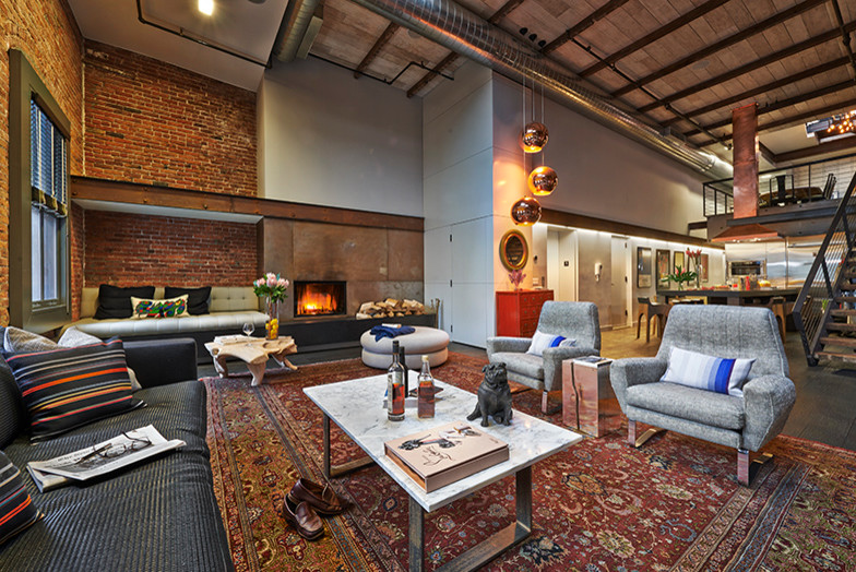 Photo of a large industrial loft-style living room in New York with white walls, a standard fireplace and a metal fireplace surround.