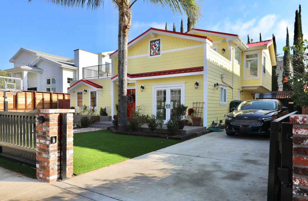 This is an example of a large modern two-storey yellow house exterior in Los Angeles with wood siding and a metal roof.