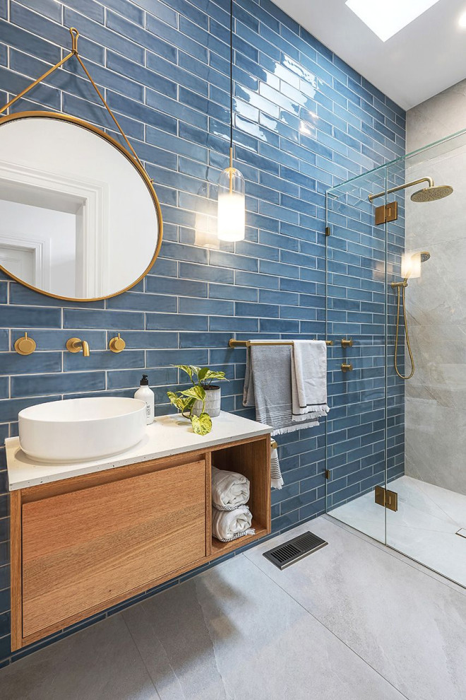 Пример оригинального дизайна: маленькая ванная комната в стиле неоклассика (современная классика) с плоскими фасадами, фасадами цвета дерева среднего тона, душевой комнатой, унитазом-моноблоком, синей плиткой, керамической плиткой, серыми стенами, полом из керамогранита, душевой кабиной, настольной раковиной, столешницей терраццо, серым полом, душем с распашными дверями, серой столешницей, нишей, тумбой под одну раковину и подвесной тумбой для на участке и в саду