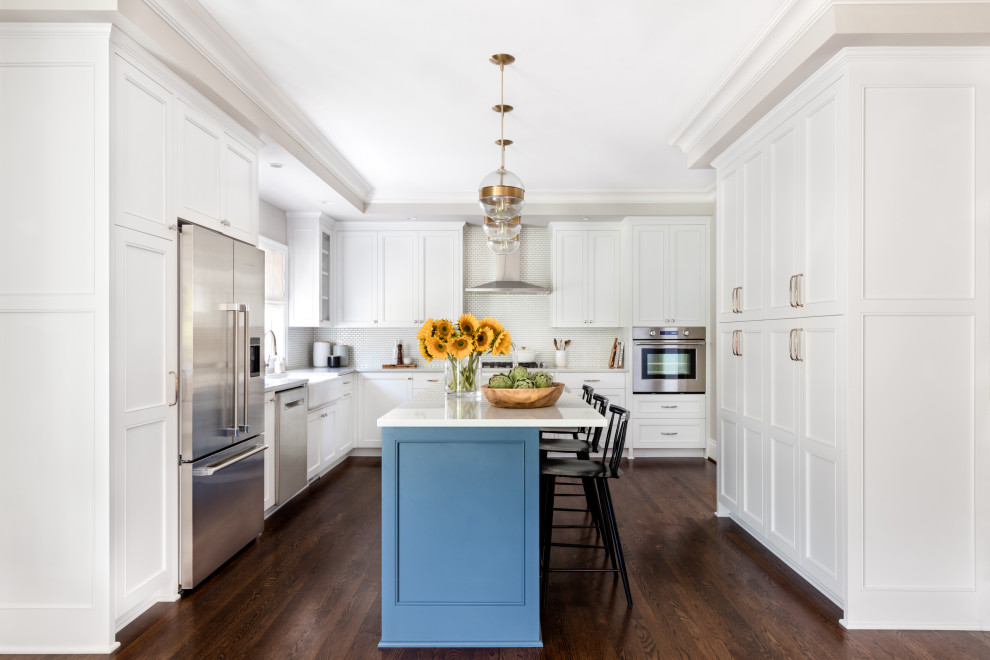Design ideas for a transitional u-shaped kitchen in Seattle with a farmhouse sink, recessed-panel cabinets, white cabinets, white splashback, mosaic tile splashback, stainless steel appliances, dark hardwood floors, with island and grey benchtop.