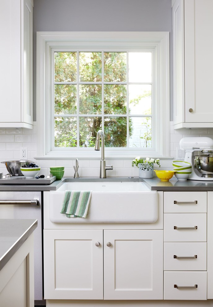 Example of a mid-sized transitional u-shaped dark wood floor and brown floor enclosed kitchen design in DC Metro with a farmhouse sink, shaker cabinets, white cabinets, solid surface countertops, white backsplash, subway tile backsplash, stainless steel appliances and an island