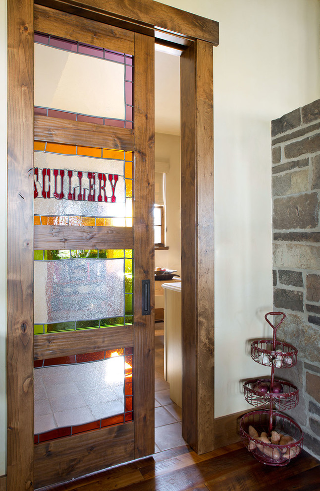 Home design - large rustic l-shaped medium tone wood floor home design idea in Denver with an undermount sink, shaker cabinets, brown cabinets, marble countertops, white backsplash, ceramic backsplash, paneled appliances and an island
