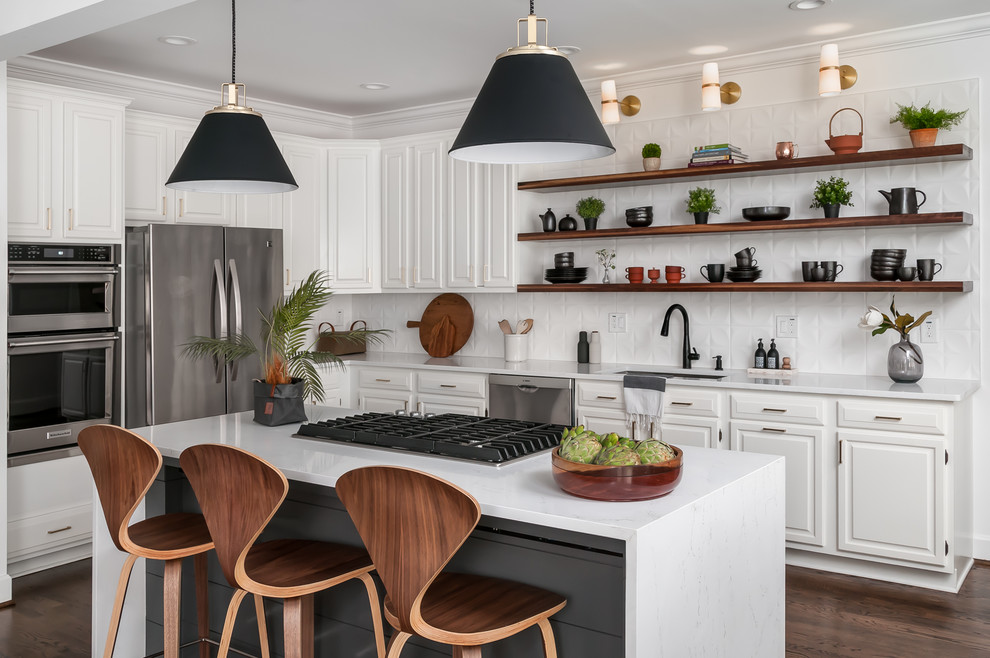 Inspiration for a mid-sized transitional l-shaped dark wood floor and brown floor kitchen remodel in Atlanta with raised-panel cabinets, white cabinets, white backsplash, stainless steel appliances, an island, white countertops, a drop-in sink, quartzite countertops and ceramic backsplash
