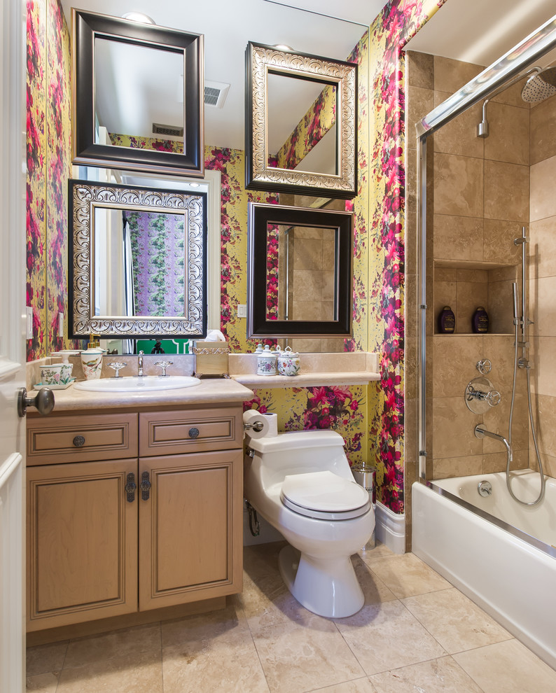 This is an example of a mediterranean bathroom in Los Angeles with a drop-in sink, raised-panel cabinets, medium wood cabinets, an alcove tub, a shower/bathtub combo, a one-piece toilet, beige tile and multi-coloured walls.