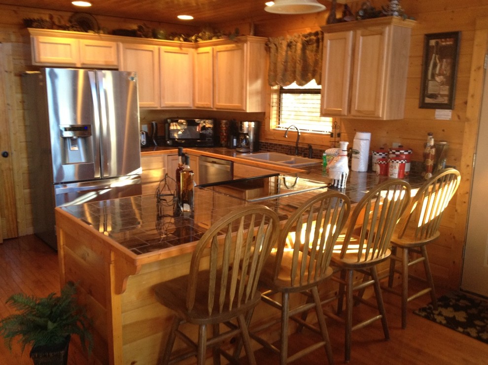 Inspiration for an u-shaped light wood floor eat-in kitchen remodel with light wood cabinets, tile countertops and stainless steel appliances