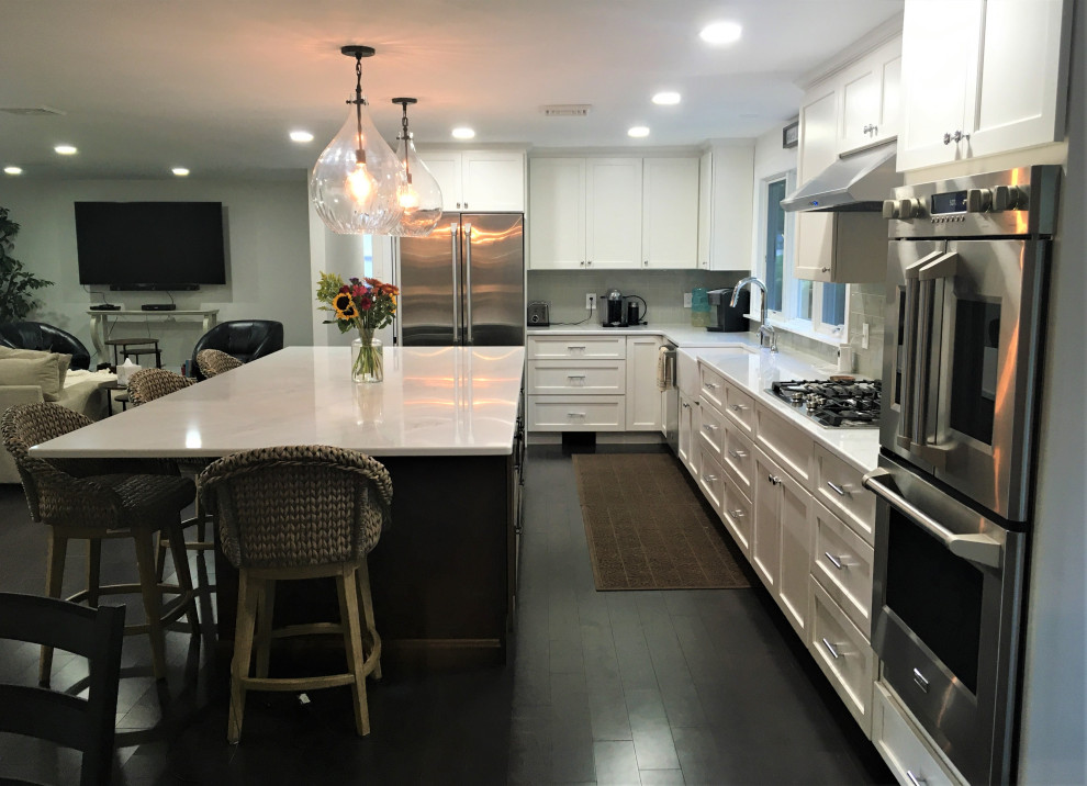 Inspiration for a huge transitional l-shaped dark wood floor and brown floor eat-in kitchen remodel in Boston with a farmhouse sink, shaker cabinets, white cabinets, quartz countertops, gray backsplash, subway tile backsplash, stainless steel appliances, an island and white countertops