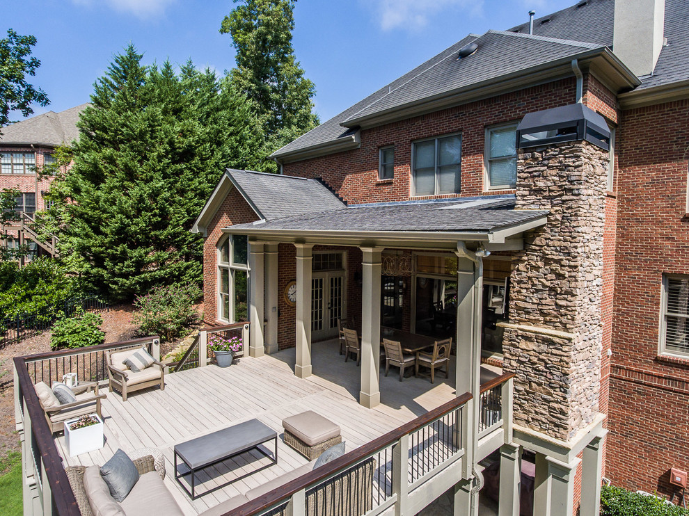 Example of a large transitional backyard deck design in Atlanta with a roof extension