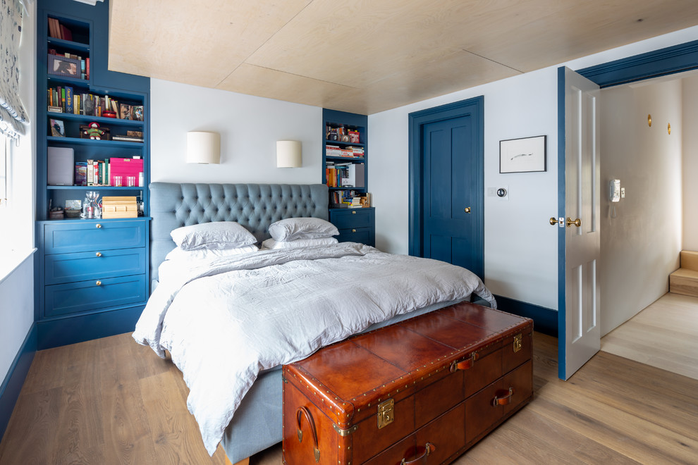 This is an example of a transitional bedroom in Vancouver with blue walls, light hardwood floors and no fireplace.