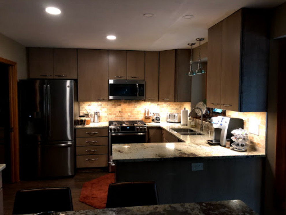 This is an example of a mid-sized eclectic u-shaped eat-in kitchen in Cleveland with an undermount sink, flat-panel cabinets, light wood cabinets, granite benchtops, multi-coloured splashback, stone tile splashback, stainless steel appliances, laminate floors, a peninsula, brown floor and multi-coloured benchtop.