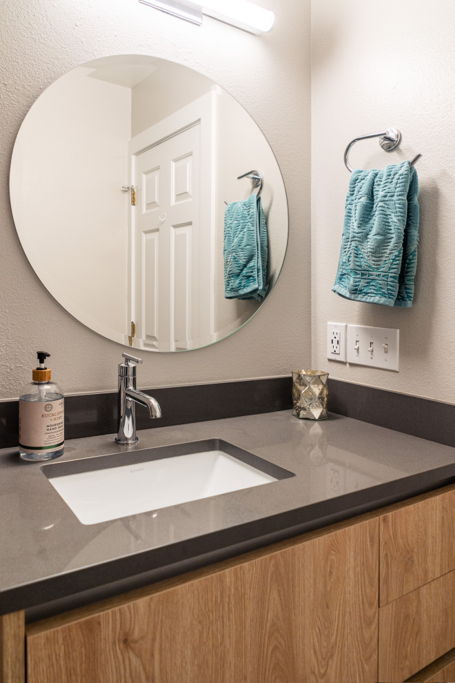 This is an example of a small contemporary 3/4 bathroom in Portland with flat-panel cabinets, brown floor, light wood cabinets, an alcove tub, an alcove shower, a one-piece toilet, white tile, subway tile, grey walls, porcelain floors, an undermount sink, engineered quartz benchtops, a hinged shower door, grey benchtops, a single vanity and a built-in vanity.