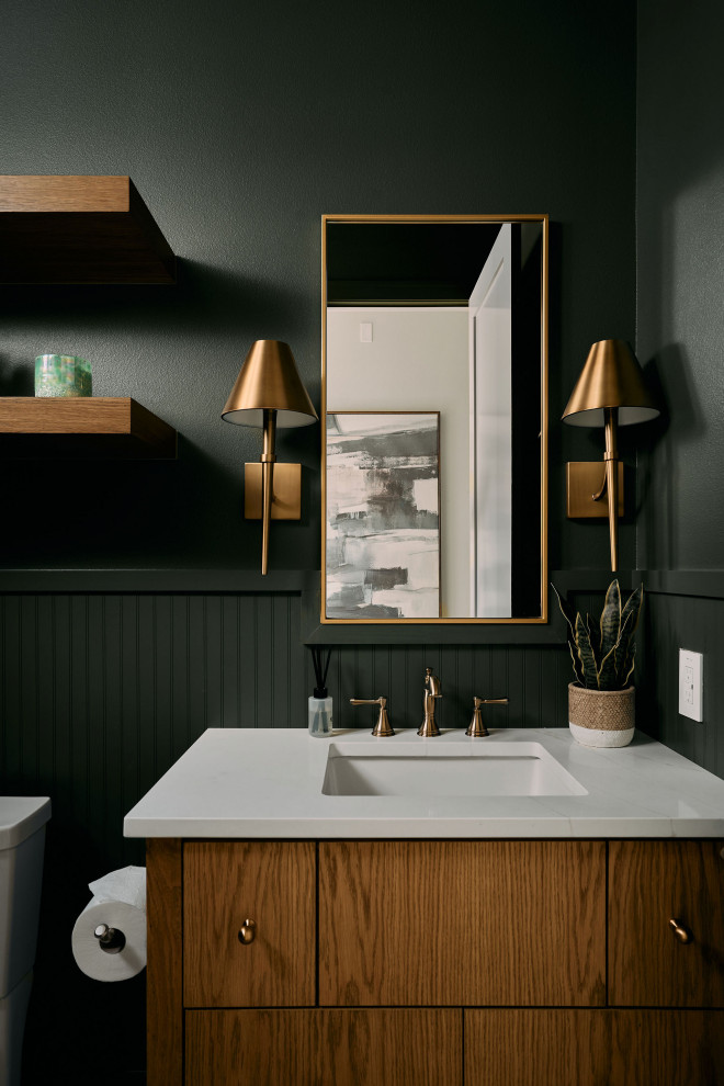 Powder room - transitional wainscoting powder room idea in Austin with flat-panel cabinets, medium tone wood cabinets, green walls, an undermount sink and white countertops