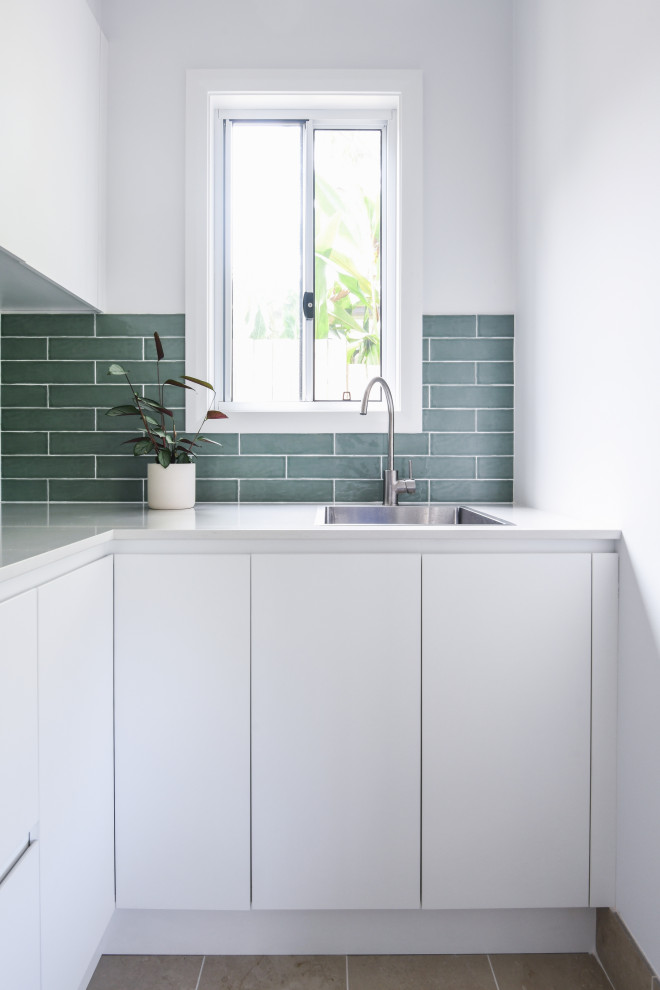 Inspiration för moderna tvättstugor, med en enkel diskho, grönt stänkskydd, vita väggar och grått golv