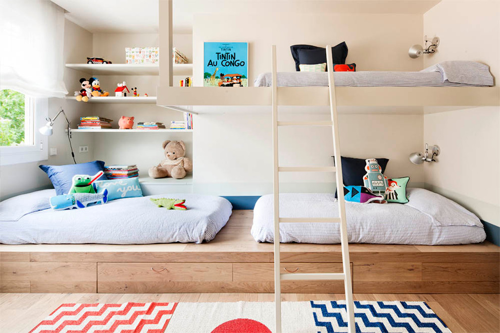 Inspiration for a mid-sized contemporary gender-neutral kids' bedroom for kids 4-10 years old in Barcelona with beige walls and light hardwood floors.