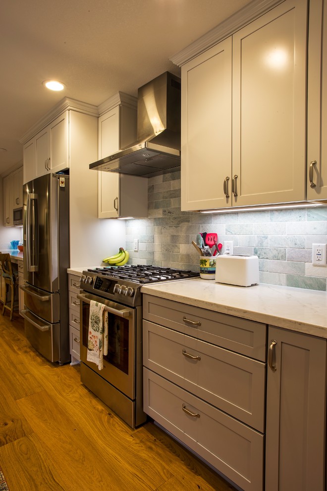 Large transitional galley light wood floor and brown floor open concept kitchen photo in Sacramento with a farmhouse sink, shaker cabinets, gray cabinets, quartz countertops, gray backsplash, stone tile backsplash, stainless steel appliances, no island and white countertops