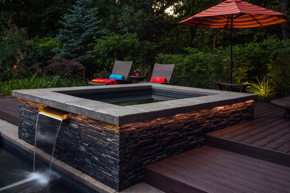 Photo of a large contemporary backyard pool in Other with a water feature and decking.