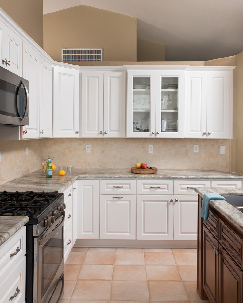 This is an example of a large traditional l-shaped kitchen in San Diego with an undermount sink, raised-panel cabinets, white cabinets, granite benchtops, beige splashback, ceramic splashback, stainless steel appliances, ceramic floors, with island and beige floor.