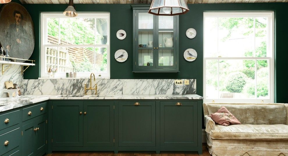 Photo of a mid-sized traditional l-shaped eat-in kitchen in London with a double-bowl sink, shaker cabinets, green cabinets, marble benchtops, stone slab splashback, black appliances, light hardwood floors and no island.