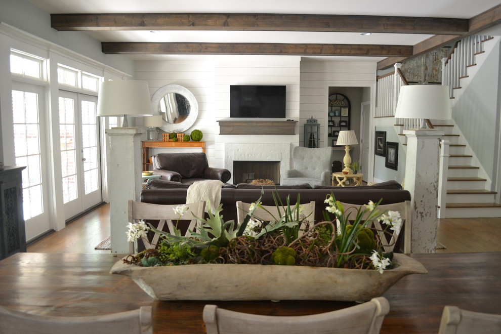 Design ideas for a mid-sized country open concept family room in Atlanta with white walls, dark hardwood floors, a standard fireplace, a brick fireplace surround, a wall-mounted tv and brown floor.