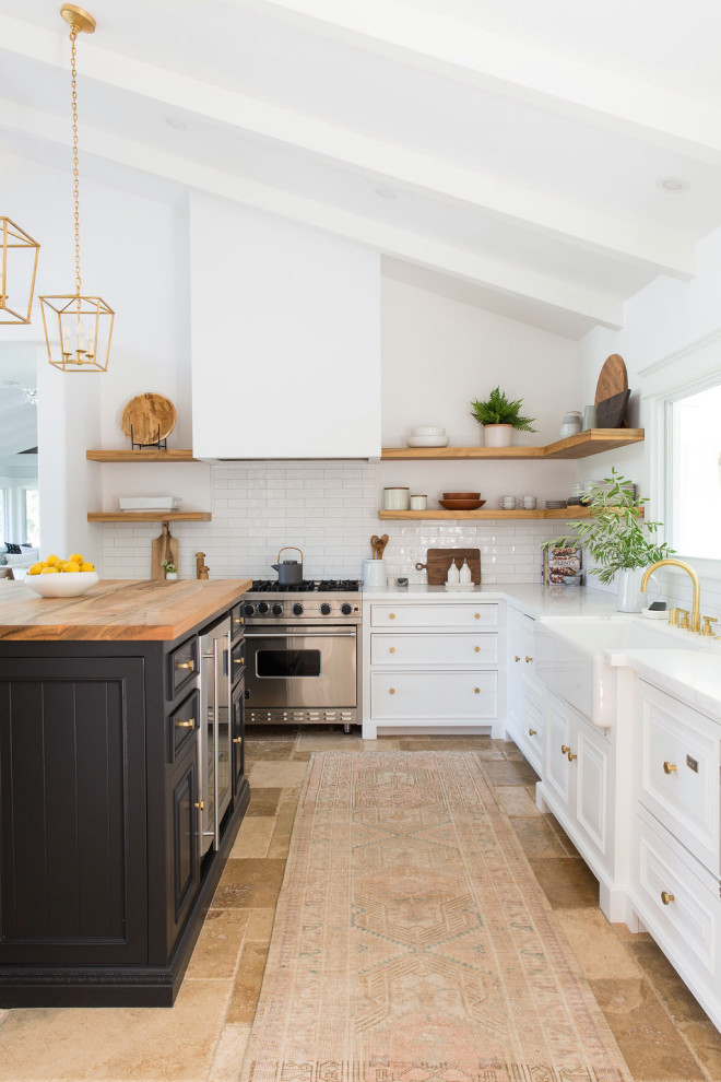 Inspiration for a large contemporary l-shaped eat-in kitchen in San Francisco with a farmhouse sink, raised-panel cabinets, white cabinets, marble benchtops, white splashback, porcelain splashback, stainless steel appliances, travertine floors, with island, multi-coloured benchtop and exposed beam.