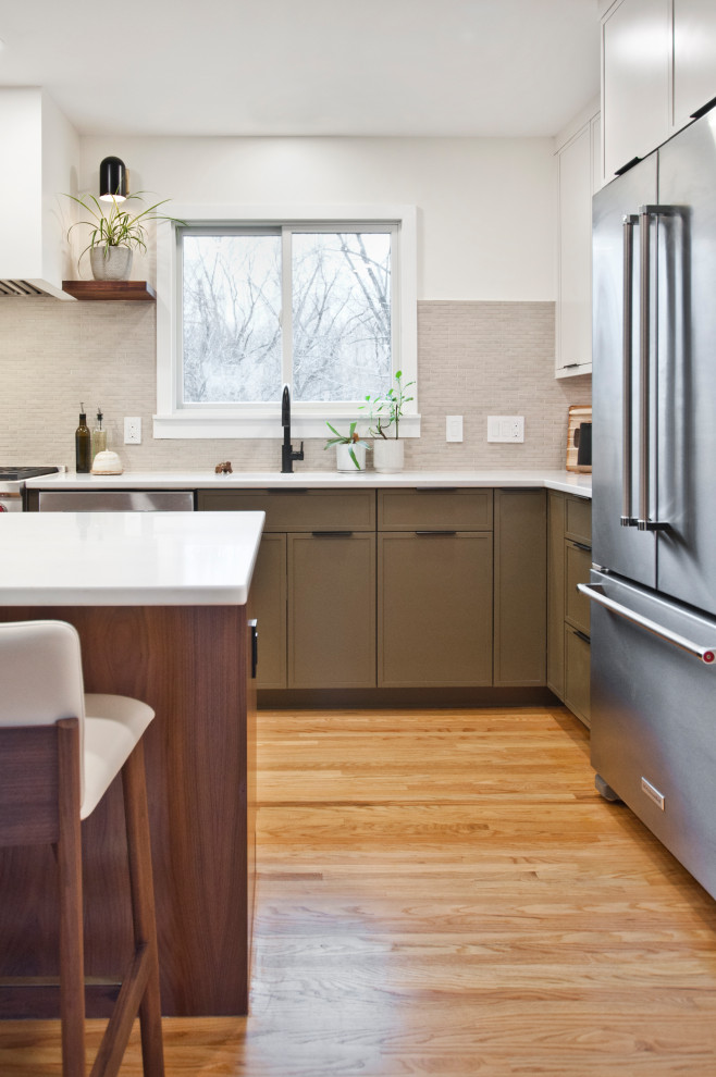 Mid-sized midcentury l-shaped eat-in kitchen in Nashville with an undermount sink, flat-panel cabinets, green cabinets, quartz benchtops, beige splashback, marble splashback, stainless steel appliances, limestone floors, with island, brown floor and white benchtop.
