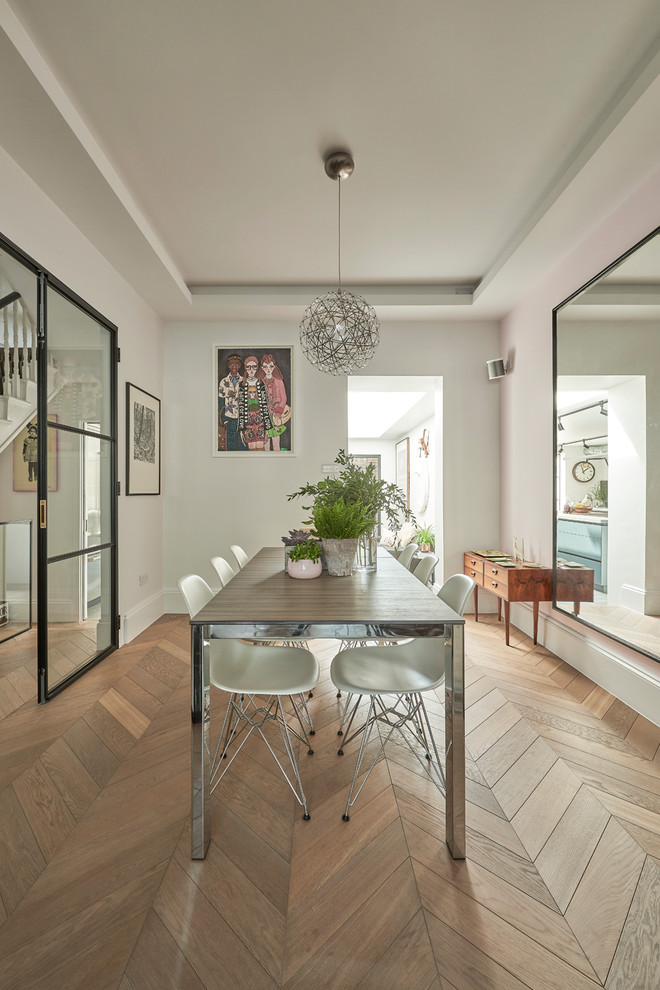 Inspiration for a mid-sized contemporary separate dining room in London with white walls, medium hardwood floors and brown floor.