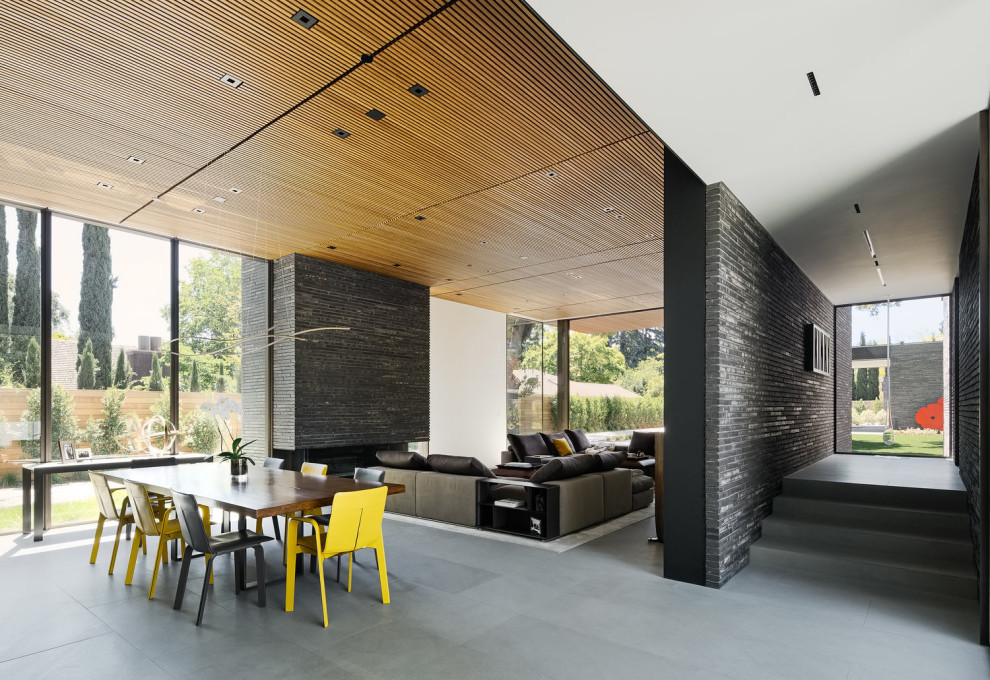 Идея дизайна: гостиная-столовая в стиле модернизм с серыми стенами, полом из керамогранита, горизонтальным камином, фасадом камина из кирпича, серым полом и деревянным потолком