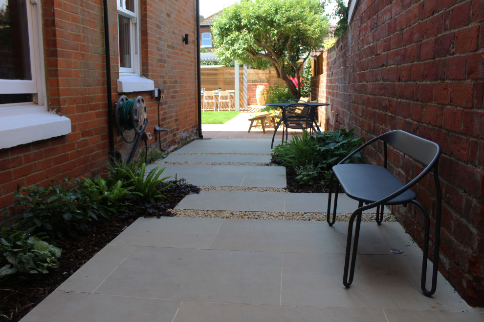 Photo of a small modern back full sun garden for summer in Hampshire with concrete paving and a wood fence.
