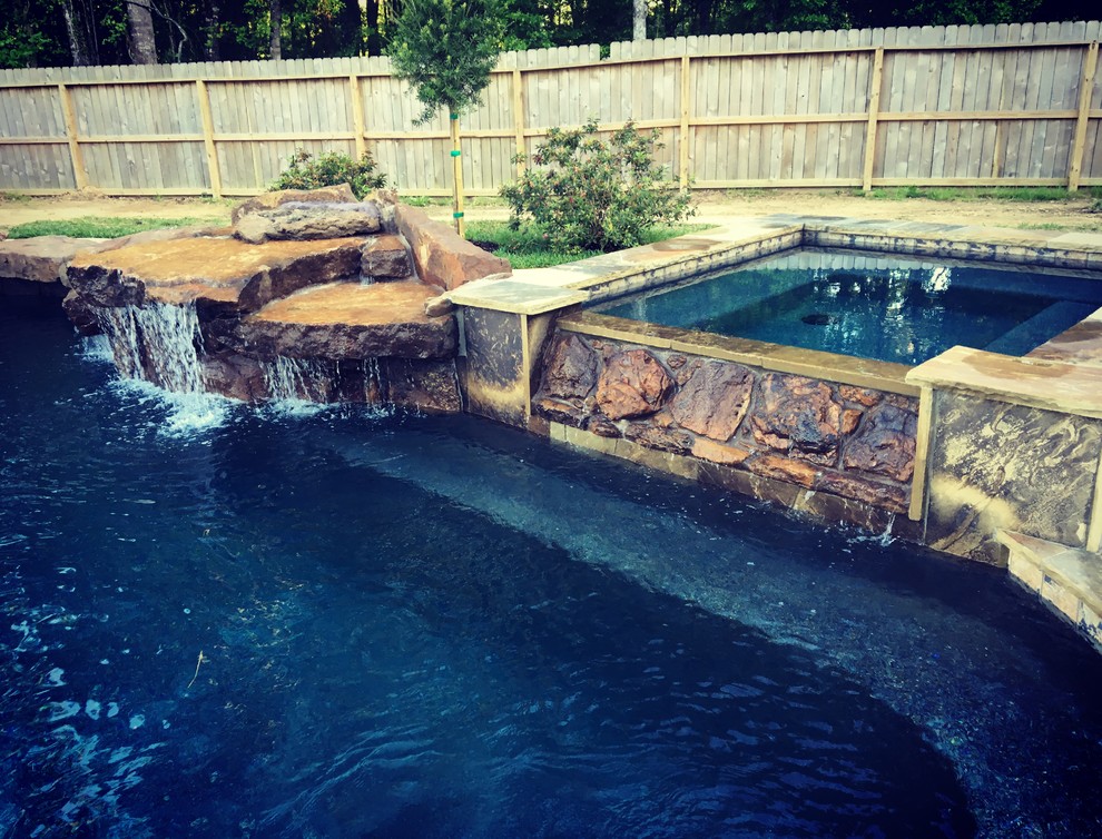 Example of a mid-sized mountain style backyard stone and custom-shaped lap hot tub design in Houston