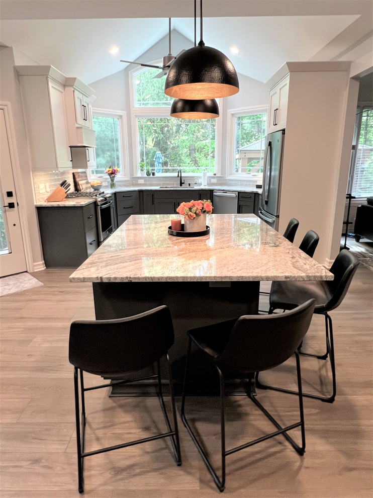 This is an example of a large traditional u-shaped kitchen/diner in Detroit with a submerged sink, recessed-panel cabinets, white cabinets, engineered stone countertops, white splashback, ceramic splashback, stainless steel appliances, light hardwood flooring, an island, grey floors and grey worktops.