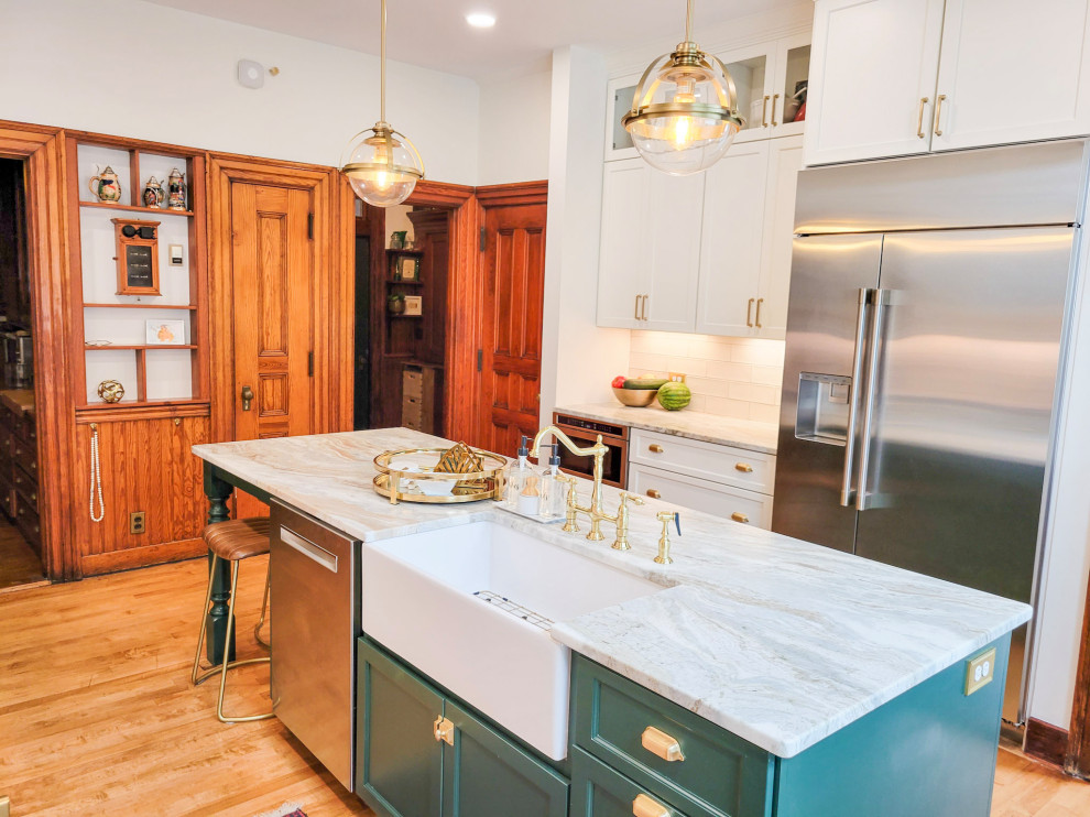 This is an example of a mid-sized traditional galley eat-in kitchen in Other with a farmhouse sink, recessed-panel cabinets, granite benchtops, white splashback, ceramic splashback, stainless steel appliances, medium hardwood floors, with island, brown floor, white benchtop and green cabinets.