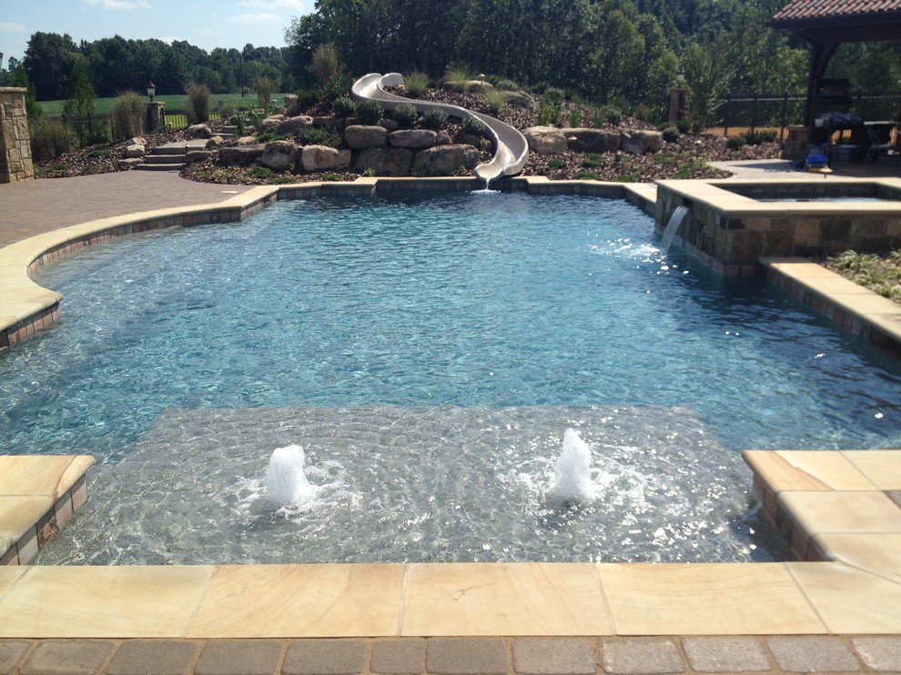 Photo of a large mediterranean backyard custom-shaped natural pool in Raleigh with concrete pavers and a water slide.