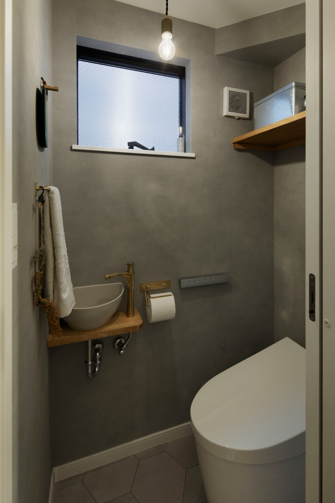 Photo of a mid-sized scandinavian powder room in Tokyo with a one-piece toilet, grey walls, grey floor and wallpaper.