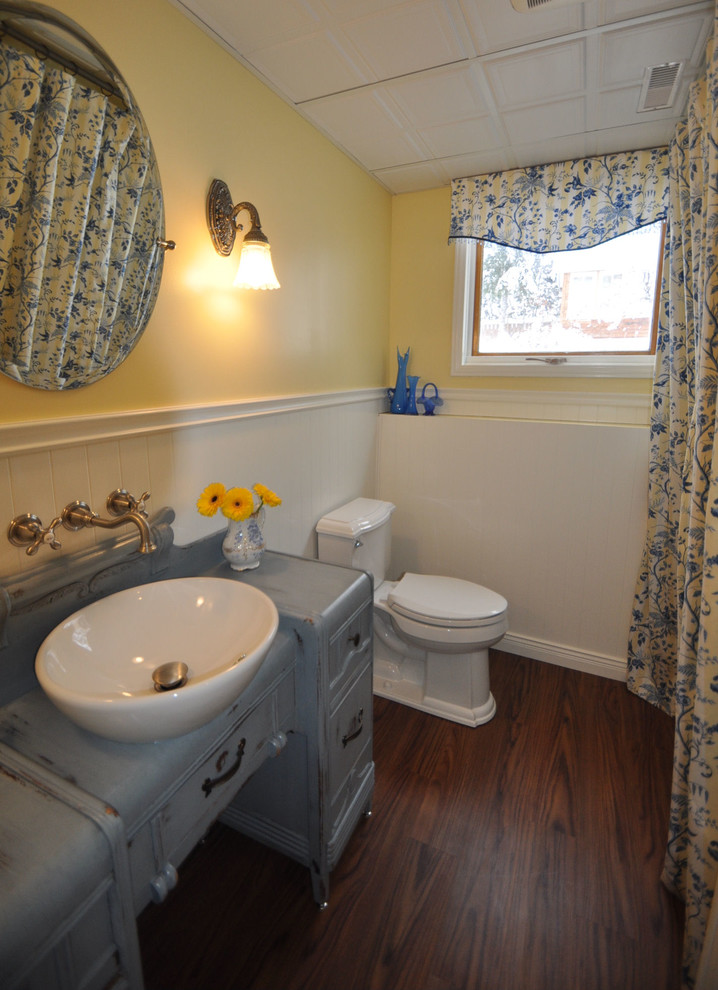 Mid-sized country bathroom in Vancouver with furniture-like cabinets, distressed cabinets, yellow walls and vinyl floors.