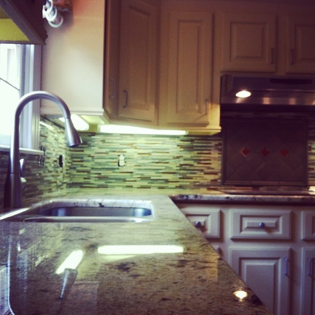 Mid-sized transitional l-shaped enclosed kitchen photo with a double-bowl sink, raised-panel cabinets, white cabinets, granite countertops, multicolored backsplash, matchstick tile backsplash, stainless steel appliances and no island