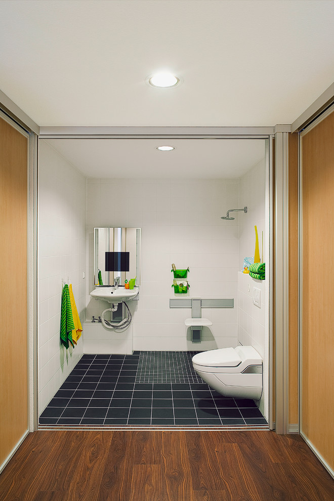 Design ideas for a mid-sized contemporary 3/4 bathroom in Bremen with flat-panel cabinets, white cabinets, an open shower, a two-piece toilet, white tile, white walls, a wall-mount sink, black floor and an open shower.