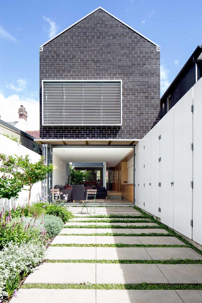 This is an example of a contemporary backyard formal garden in Sydney with a garden path and concrete pavers.