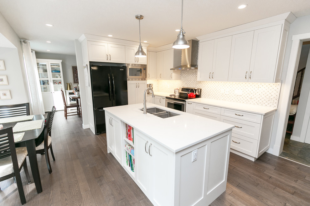Eat-in kitchen - large transitional l-shaped medium tone wood floor and brown floor eat-in kitchen idea in Calgary with shaker cabinets, white cabinets, quartz countertops, white backsplash, an island, an undermount sink and black appliances