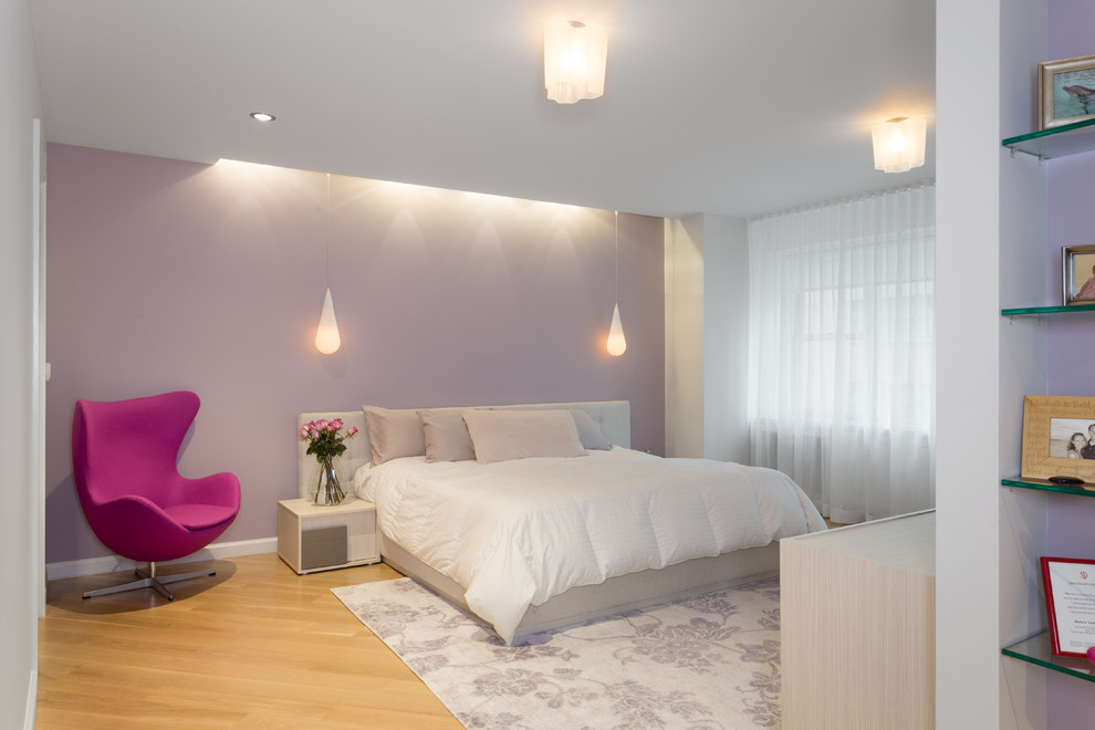 Photo of a large modern guest bedroom in New York with purple walls and light hardwood floors.