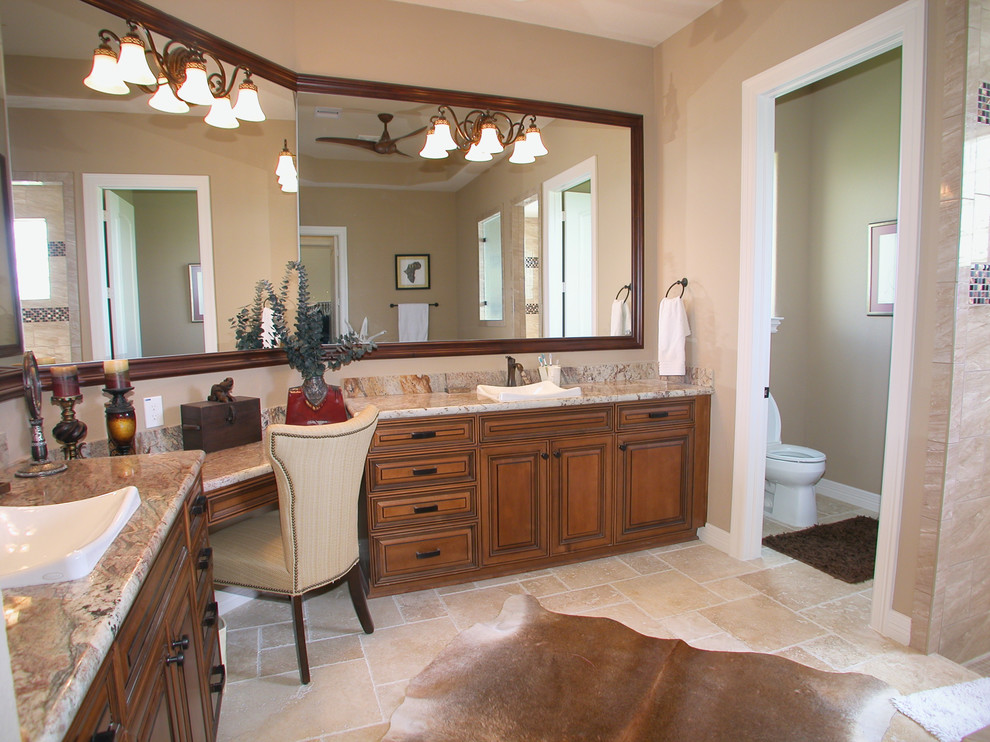 Photo of a large traditional master bathroom in Houston with a vessel sink, raised-panel cabinets, dark wood cabinets, granite benchtops, a drop-in tub, a double shower, a one-piece toilet, beige tile, stone tile, beige walls and travertine floors.