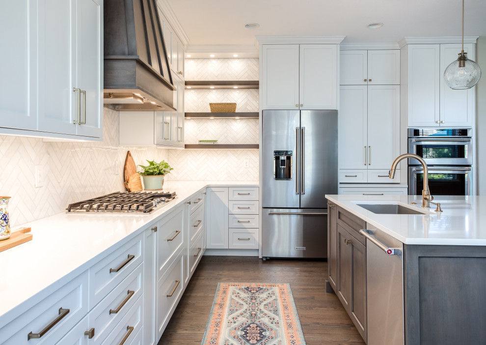 Photo of a large transitional galley open plan kitchen in Denver with an undermount sink, shaker cabinets, white cabinets, quartz benchtops, beige splashback, marble splashback, stainless steel appliances, medium hardwood floors, with island, brown floor and white benchtop.