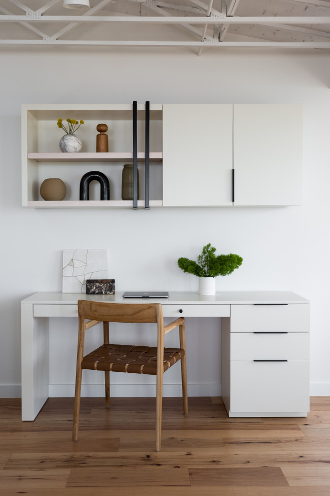 Imagen de despacho costero pequeño con paredes blancas, suelo de madera en tonos medios, escritorio independiente, suelo beige y vigas vistas