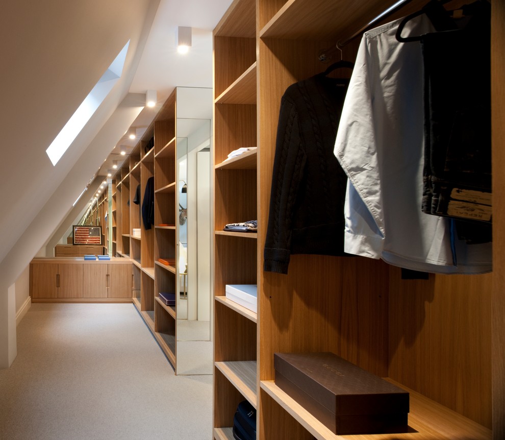 This is an example of a large contemporary men's walk-in wardrobe in London with medium wood cabinets, carpet and open cabinets.