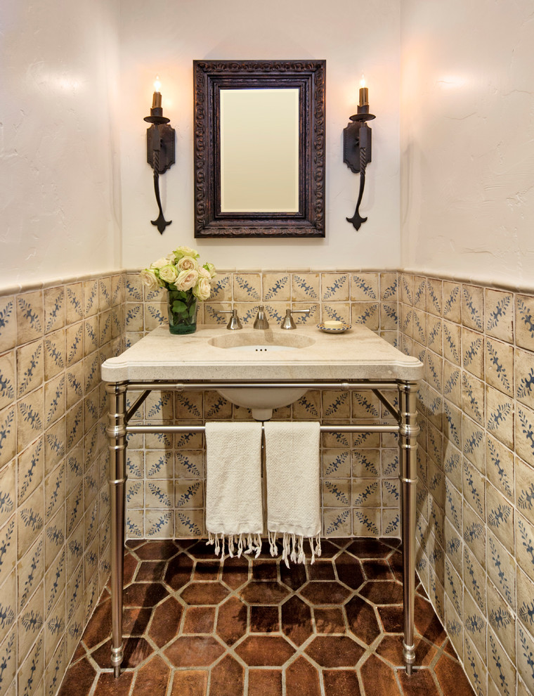 Photo of a small mediterranean powder room in Santa Barbara with multi-coloured tile, ceramic tile, white walls, terra-cotta floors, solid surface benchtops, brown floor and a console sink.